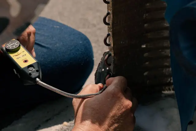 Clamp meter leads on the wiring of an outdoor AC unit