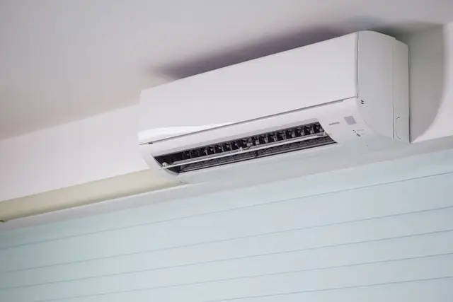 White ductless mini-split head mounted high on a living room wall
