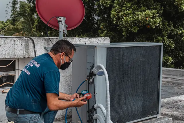 Technician testing a condensing unit with a meter on a sunny day